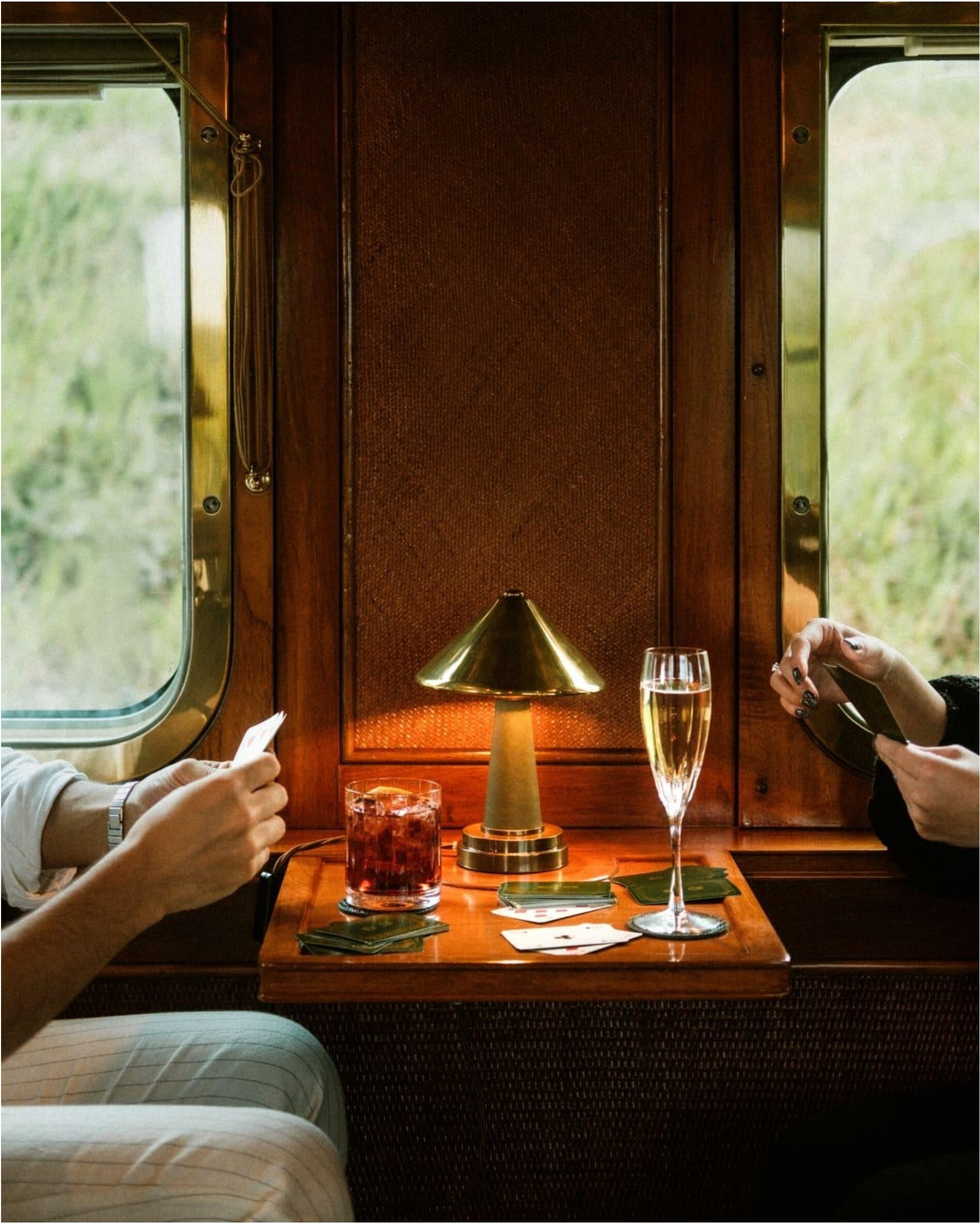 Two passengers playing cards inside a luxurious train compartment