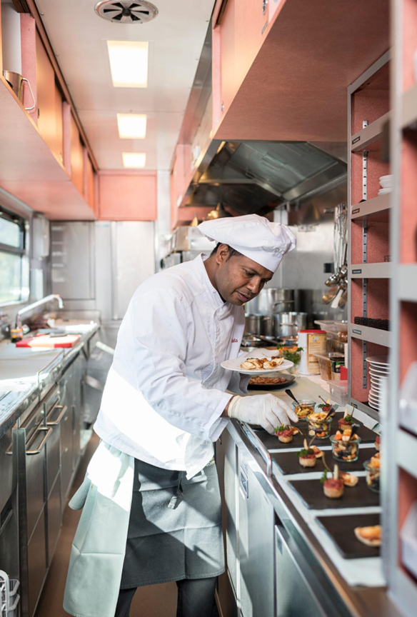 A chef plating fine cuisine inside the galley kitchen of a luxury Swiss train.