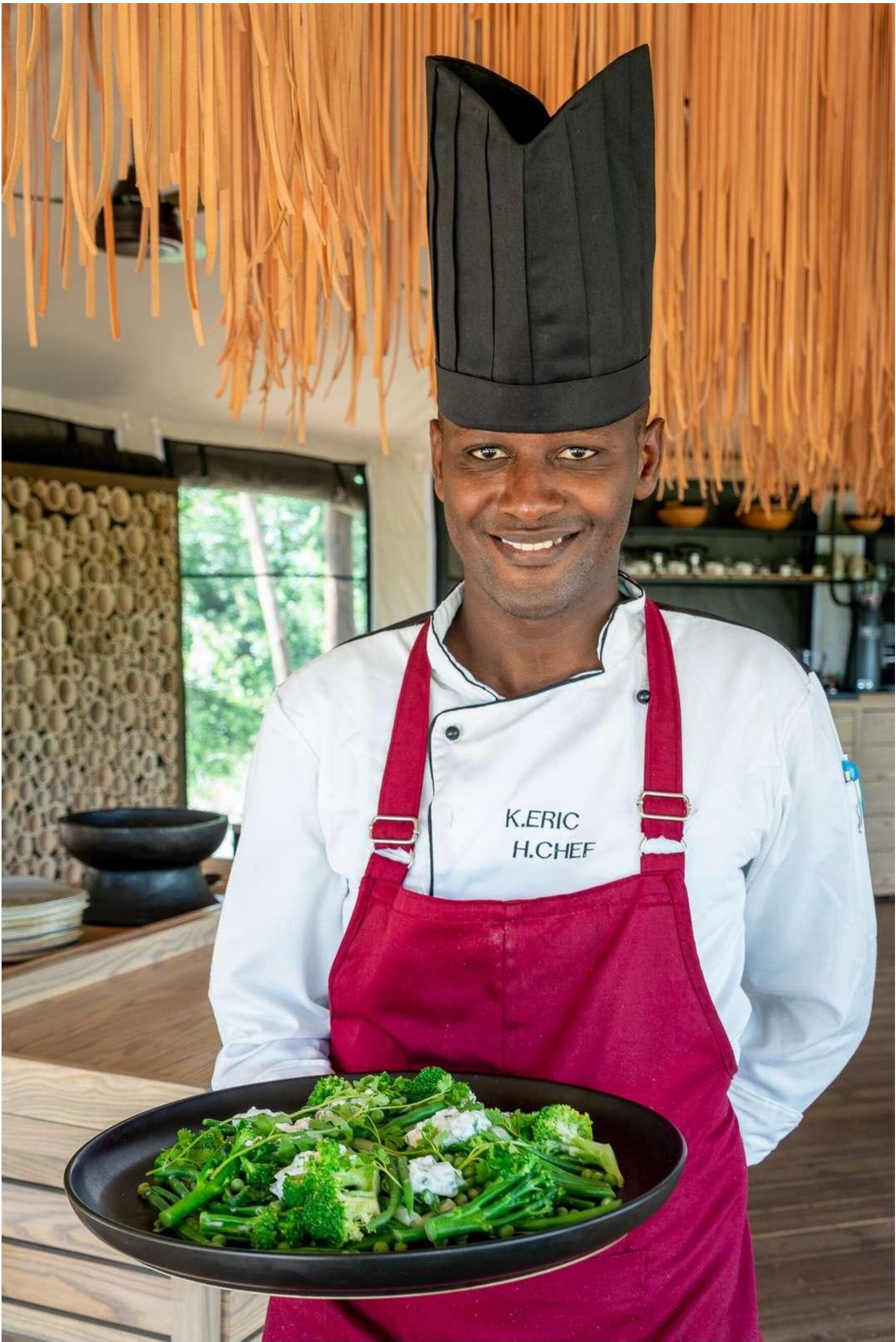 A Rwandan chef holding a plate of fresh greens