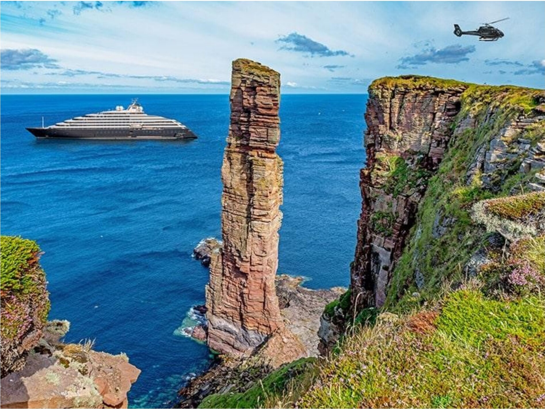 A helicopter flying past a rugged Scottish sea stack along the coast