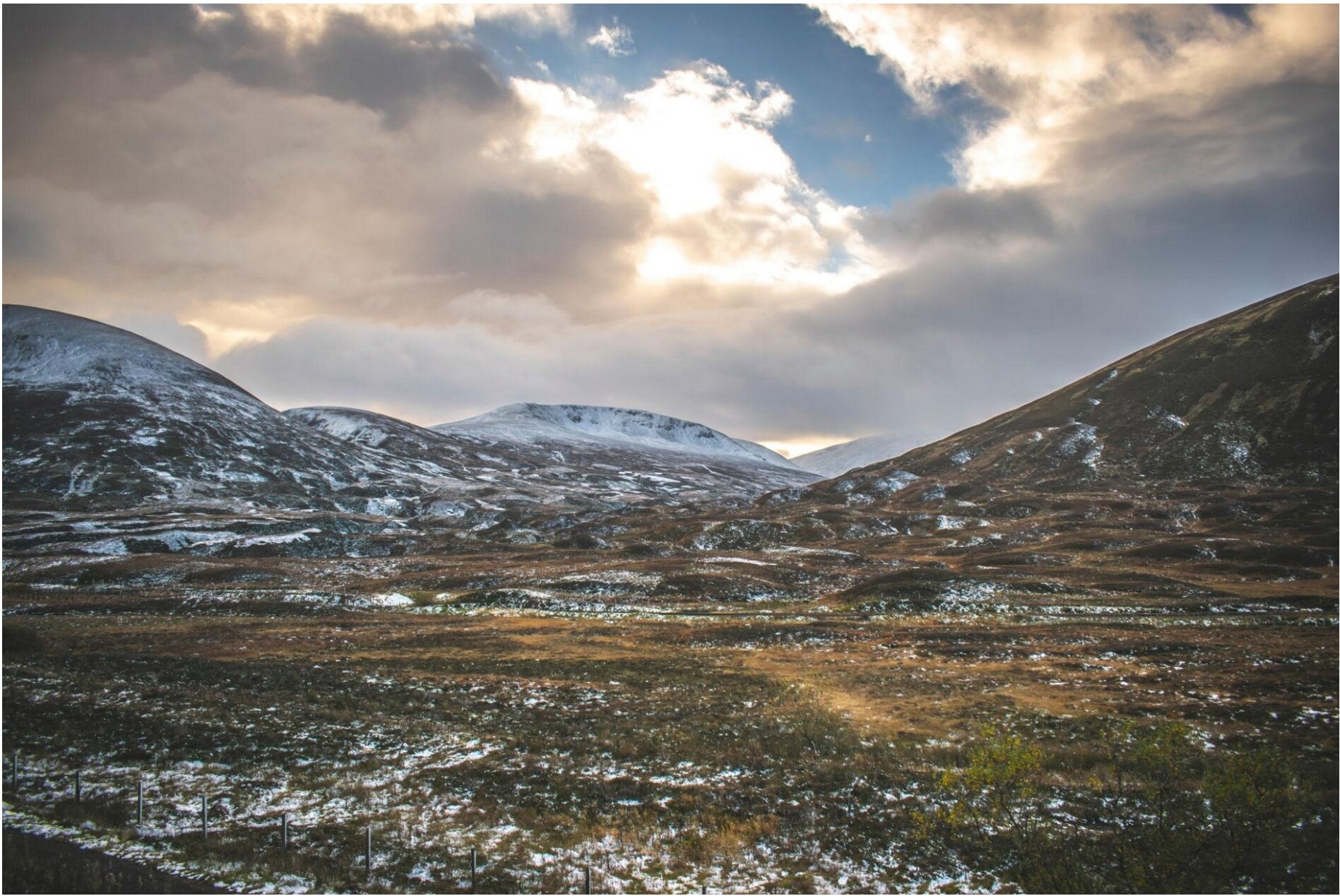 Snow-dusted Highland mountains under a dramatic cloudy sky