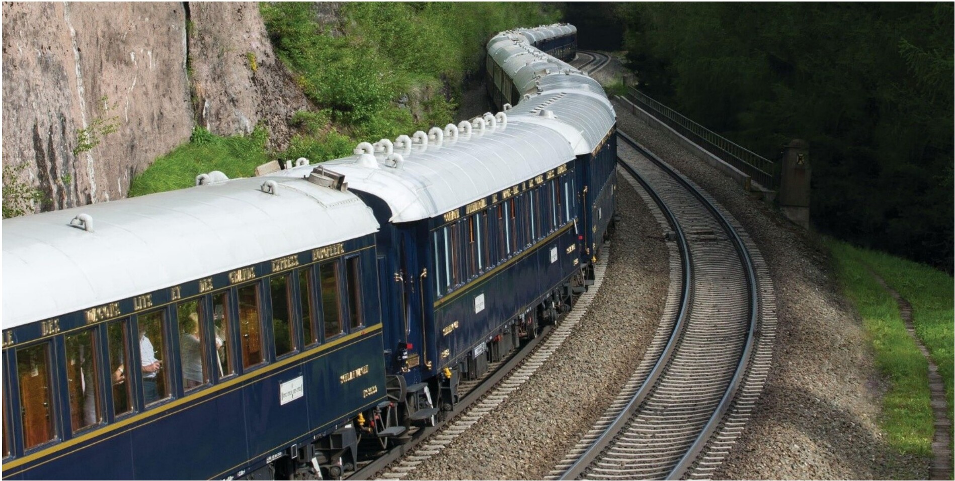 Vintage blue Venice Simplon-Orient-Express train curving through a green landscape